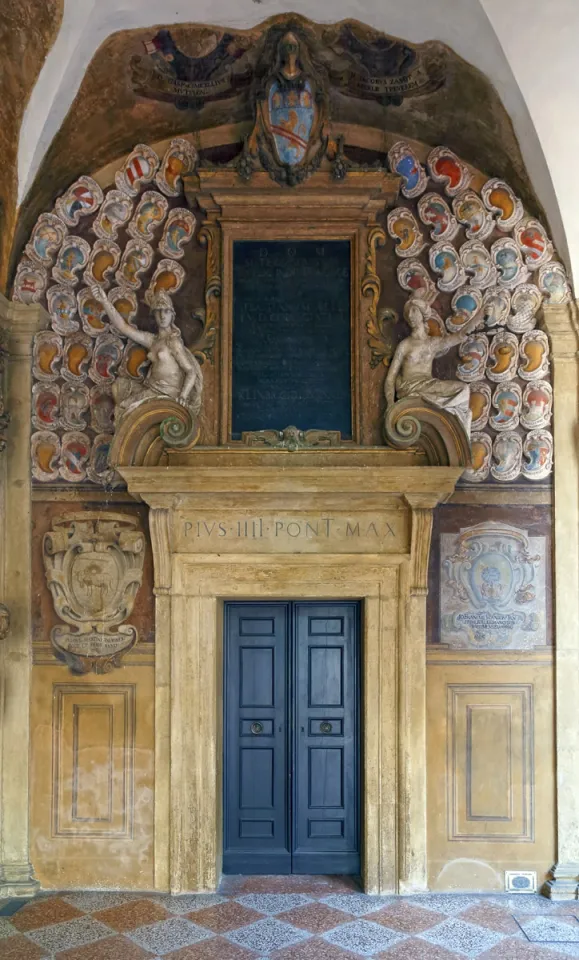 Palast des Archiginnasio, Arkade im Erdgeschoss mit Tür und Wappenreliefs