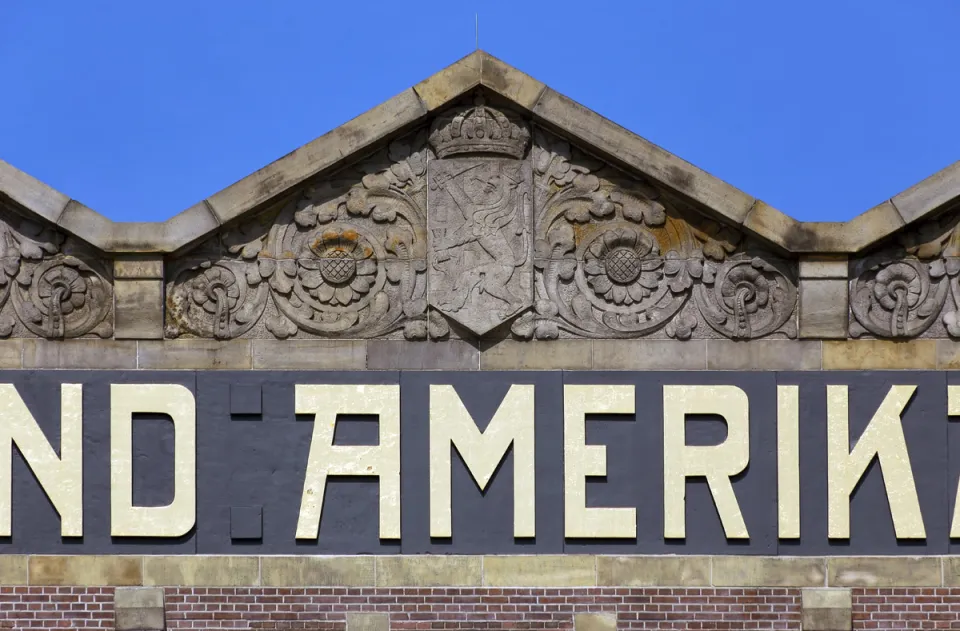 Hotel New York, Detail des Giebelreliefs und des Firmenschriftzugs